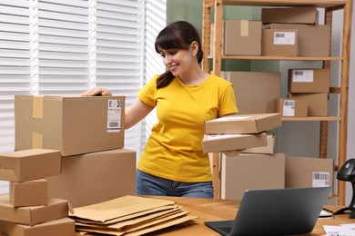 Photo of Parcel packing. Post office worker with parcels at wooden table indoors