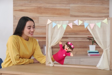 Photo of Young woman performing puppet show at home
