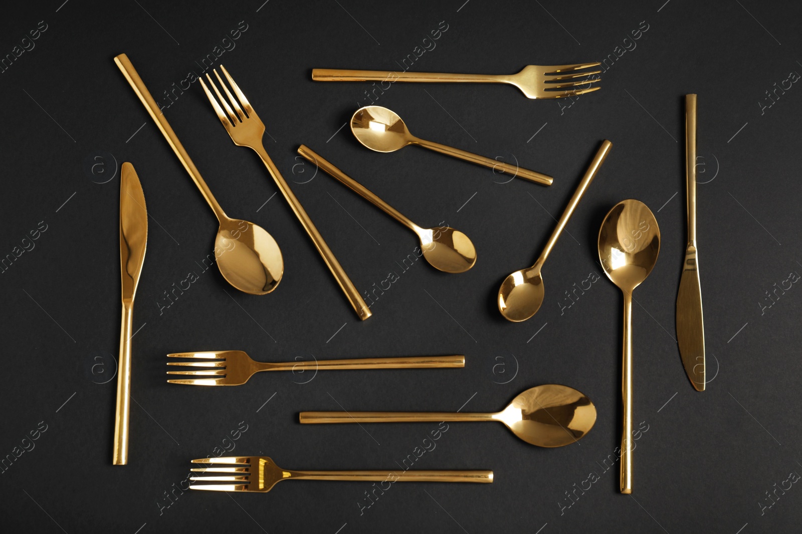 Photo of Flat lay composition with gold cutlery on black background