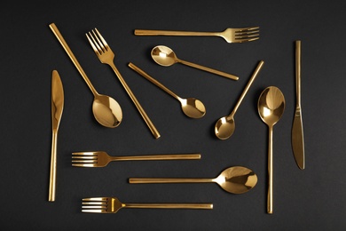 Photo of Flat lay composition with gold cutlery on black background