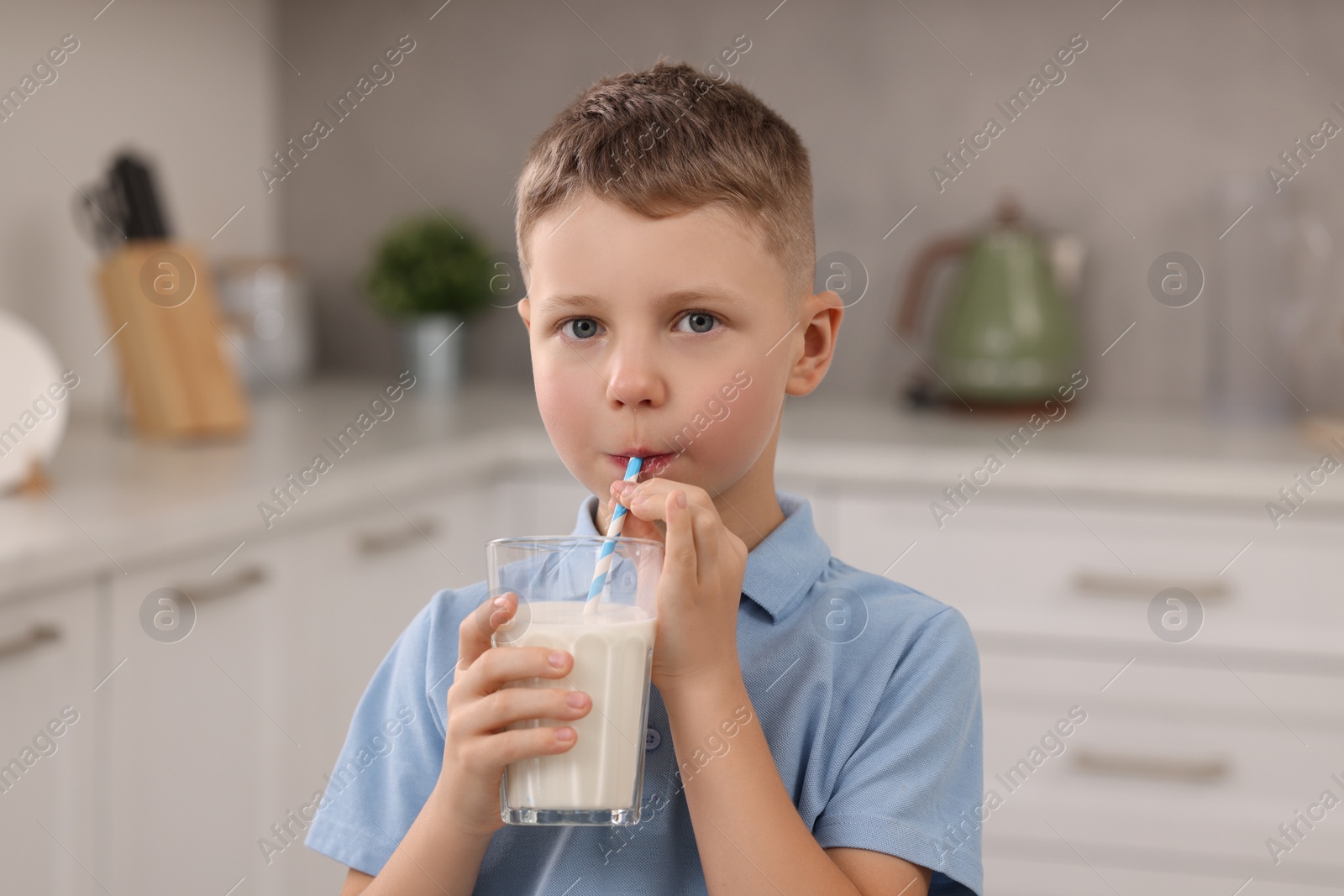 Photo of Cute boy drinking fresh milk from glass indoors