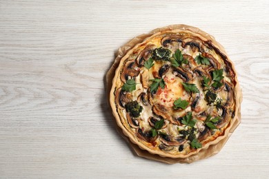 Delicious quiche with mushrooms and parsley on white wooden table, top view. Space for text