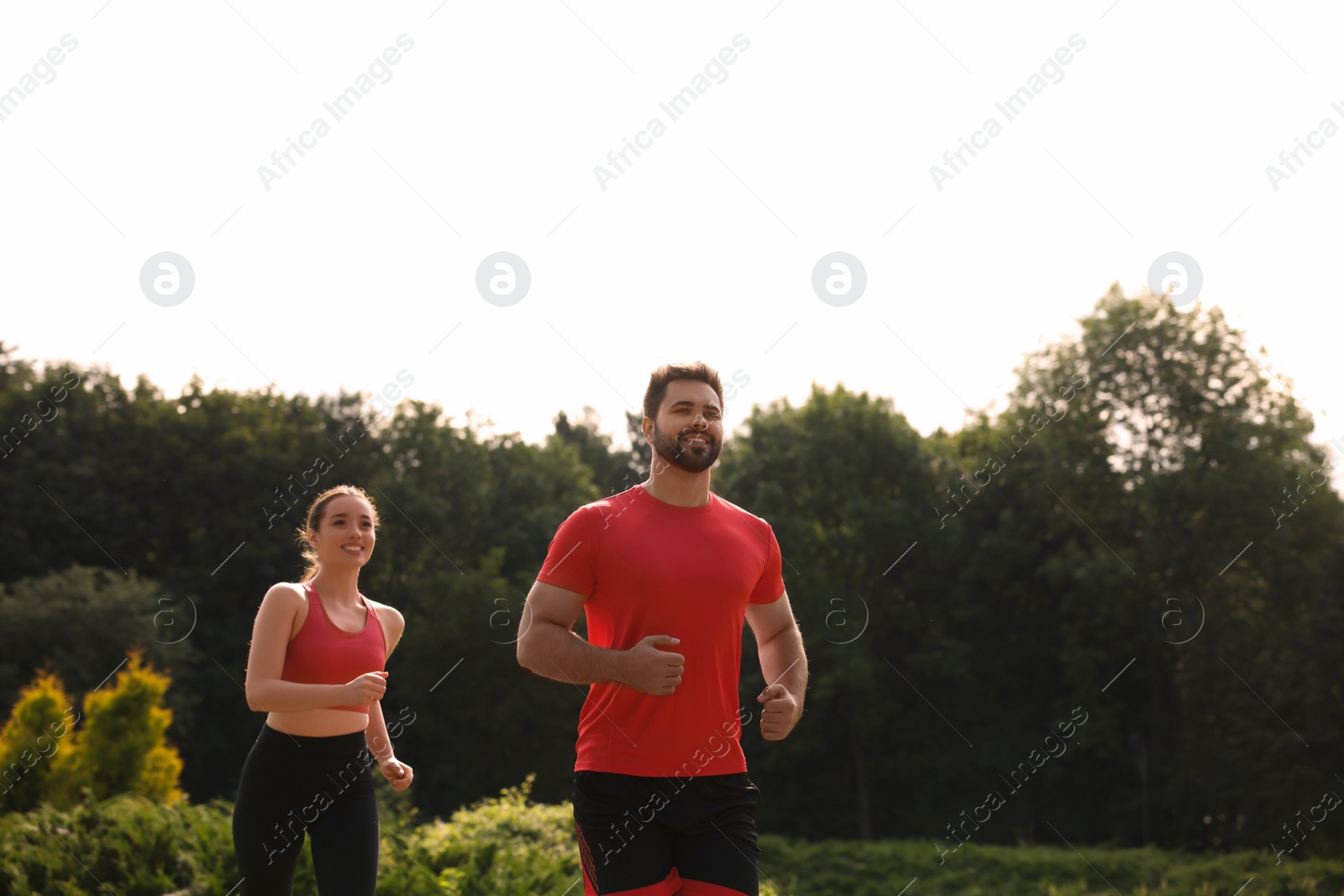 Photo of Healthy lifestyle. Happy couple running outdoors on sunny day, space for text