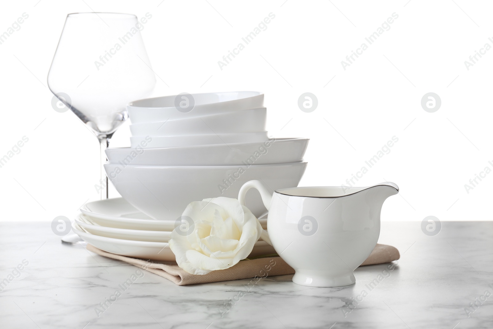 Photo of Dishware, glass, napkin and eustoma flower on light marble table, space for text