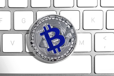 Silver bitcoin on computer keyboard, top view. Digital currency