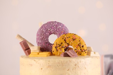 Delicious cake decorated with sweets on light background, closeup