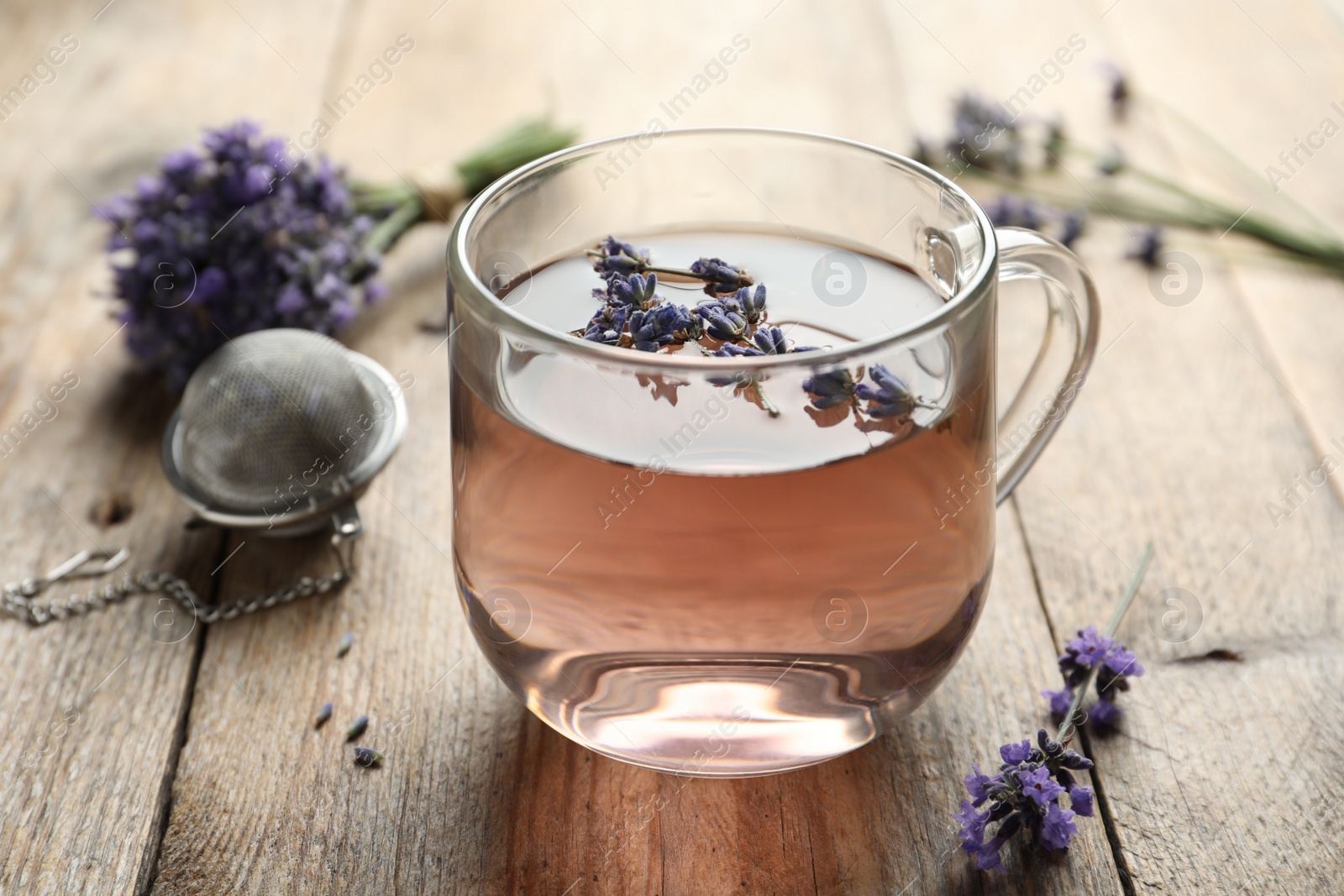 Photo of Fresh delicious tea with lavender in glass cup on wooden table