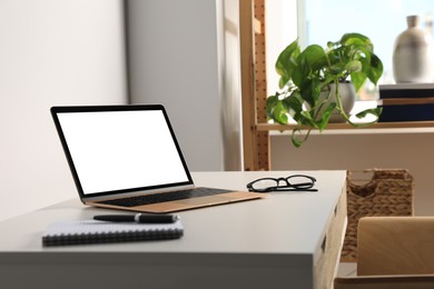 Photo of Workplace with modern laptop and glasses on white table. Mockup for design
