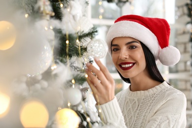 Photo of Happy young woman decorating Christmas tree at home
