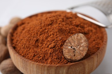 Photo of Nutmeg powder in wooden bowl on table, closeup