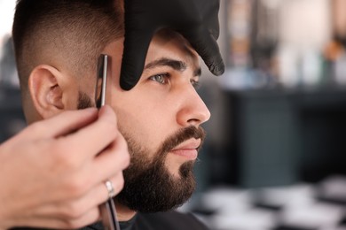 Professional hairdresser working with client in barbershop, closeup