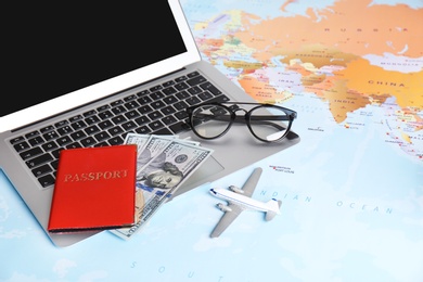 Photo of Composition with laptop, toy plane, money and passport on map. Travel agency