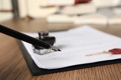 Signing document with fountain pen on wooden table, closeup. Notary contract