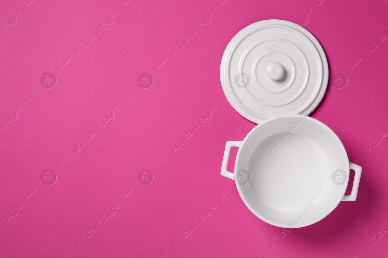 Photo of White empty pot and lid on dark pink background, flat lay. Space for text