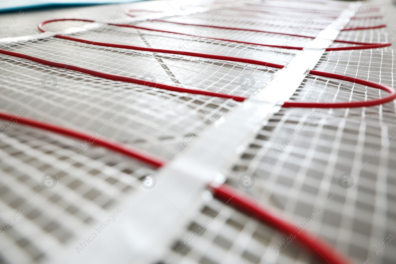 Photo of Installation of modern underfloor trace heating system indoors, closeup