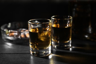 Photo of Alcohol addiction. Whiskey in glasses on black wooden table