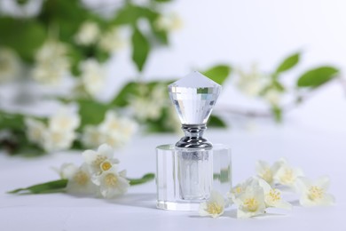 Photo of Aromatic perfume in bottle and beautiful jasmine flowers on white background