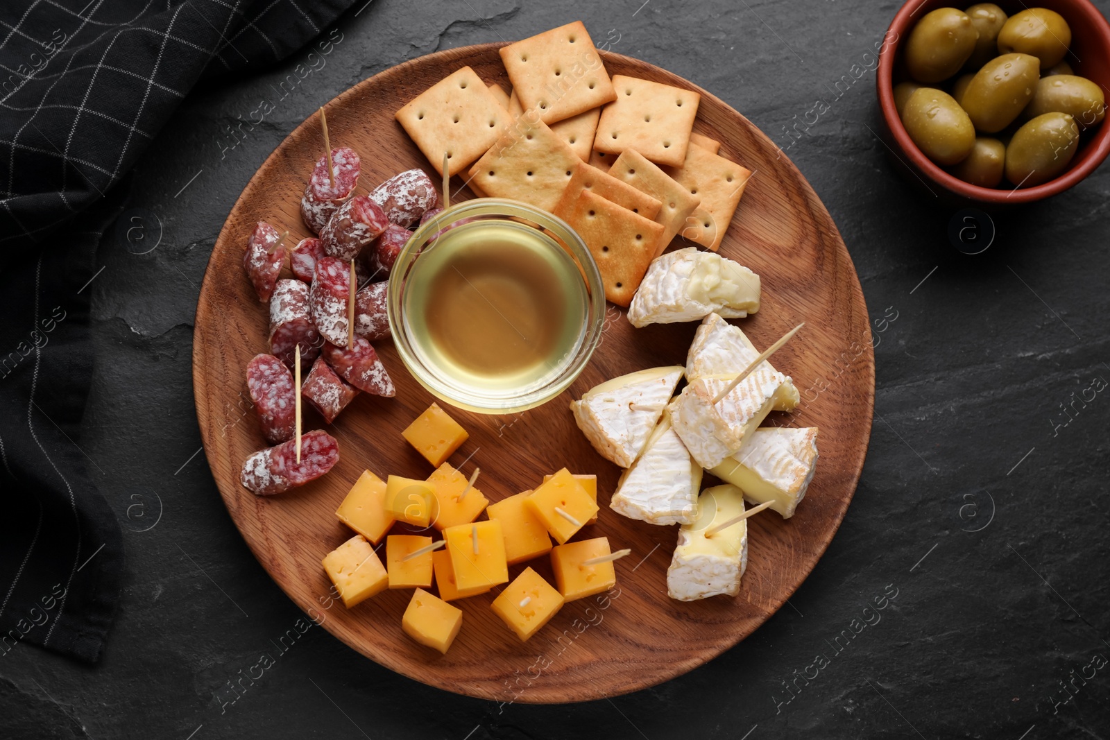 Photo of Toothpick appetizers. Pieces of cheese, sausage and honey on black table, flat lay