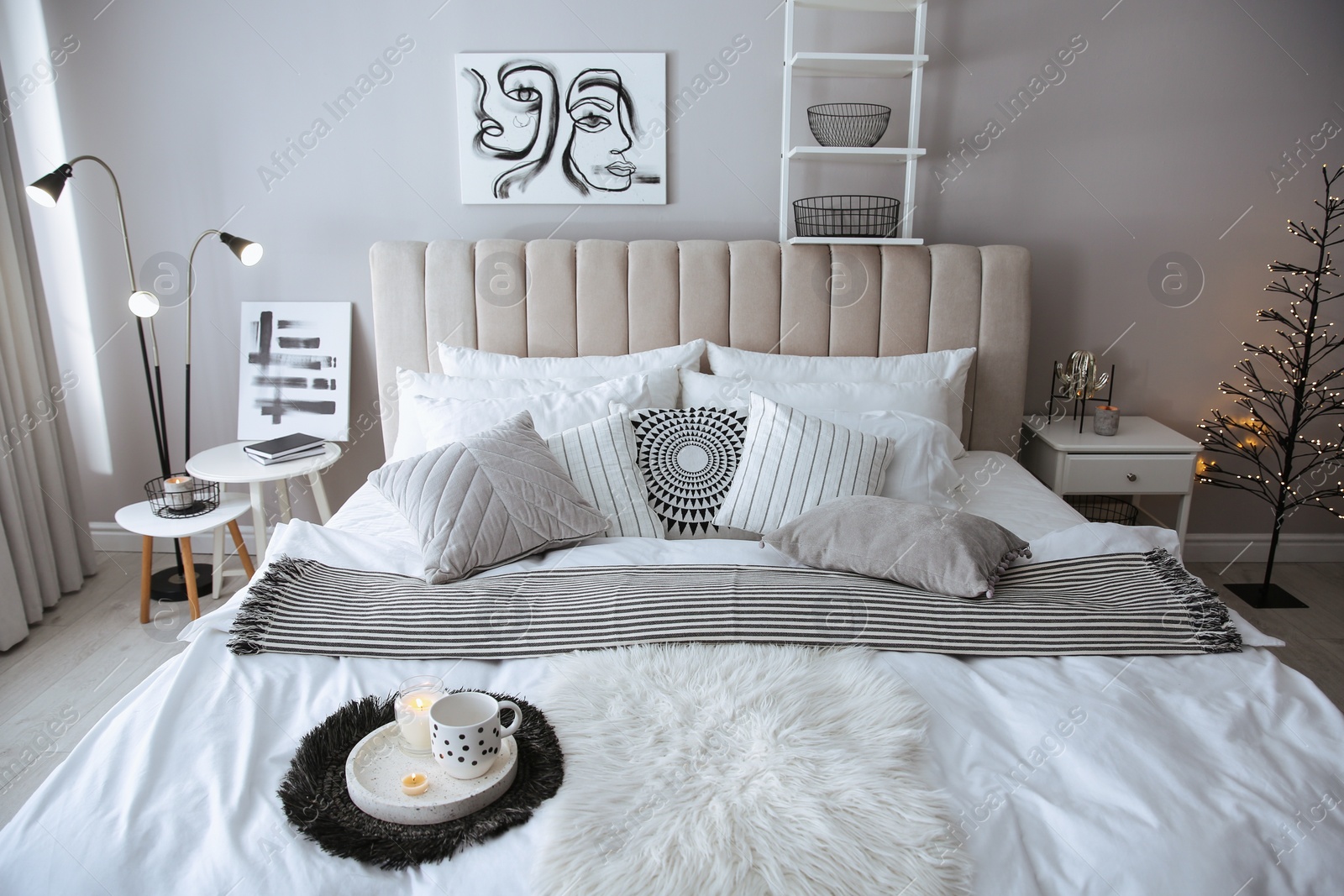 Photo of Cozy bedroom interior with cushions and striped blanket