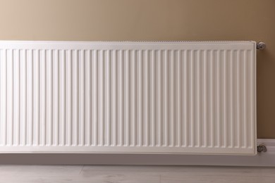 Photo of Modern radiator on beige wall. Central heating system
