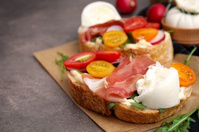 Delicious sandwiches with burrata cheese, ham and tomatoes on brown textured table, closeup. Space for text