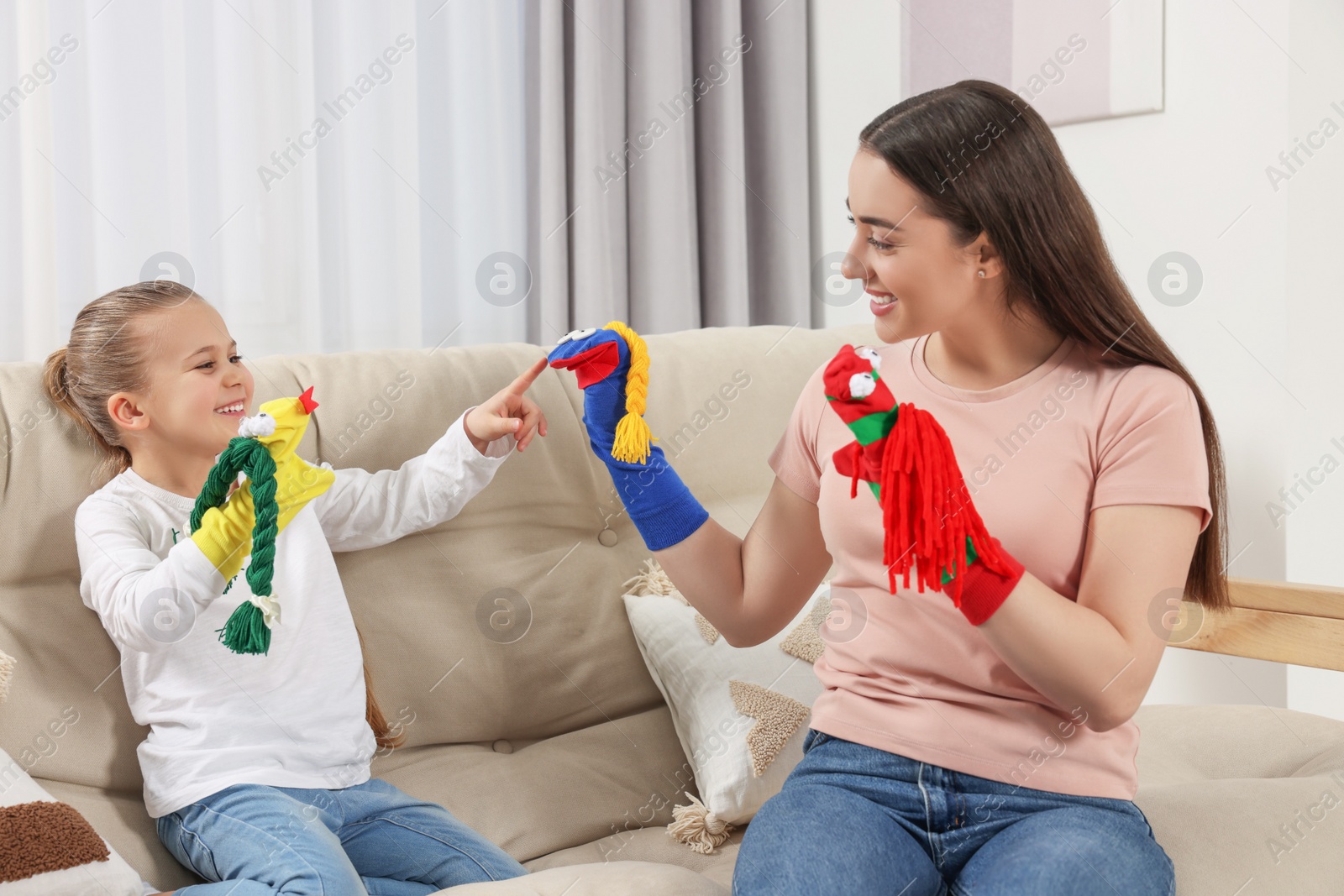 Photo of Happy mother and daughter playing with funny sock puppets together at home