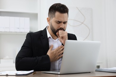 Photo of Sick man coughing at workplace in office