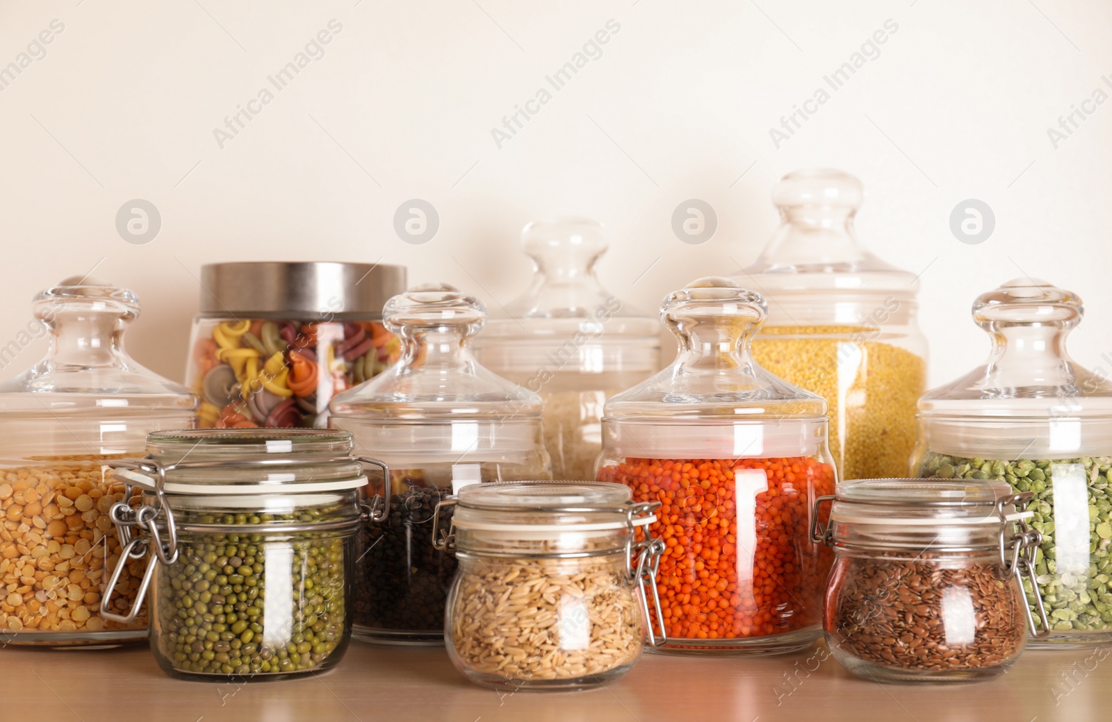 Photo of Glass jars with different types of groats on wooden shelf