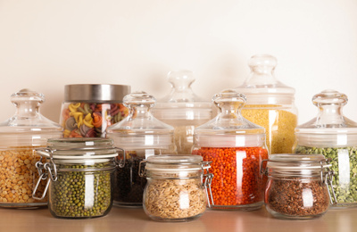 Photo of Glass jars with different types of groats on wooden shelf