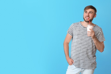 Photo of Young man with cup of delicious milk shake on color background