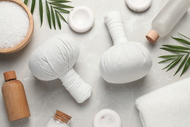 Photo of Flat lay composition with herbal massage bags and other spa products on light grey marble table