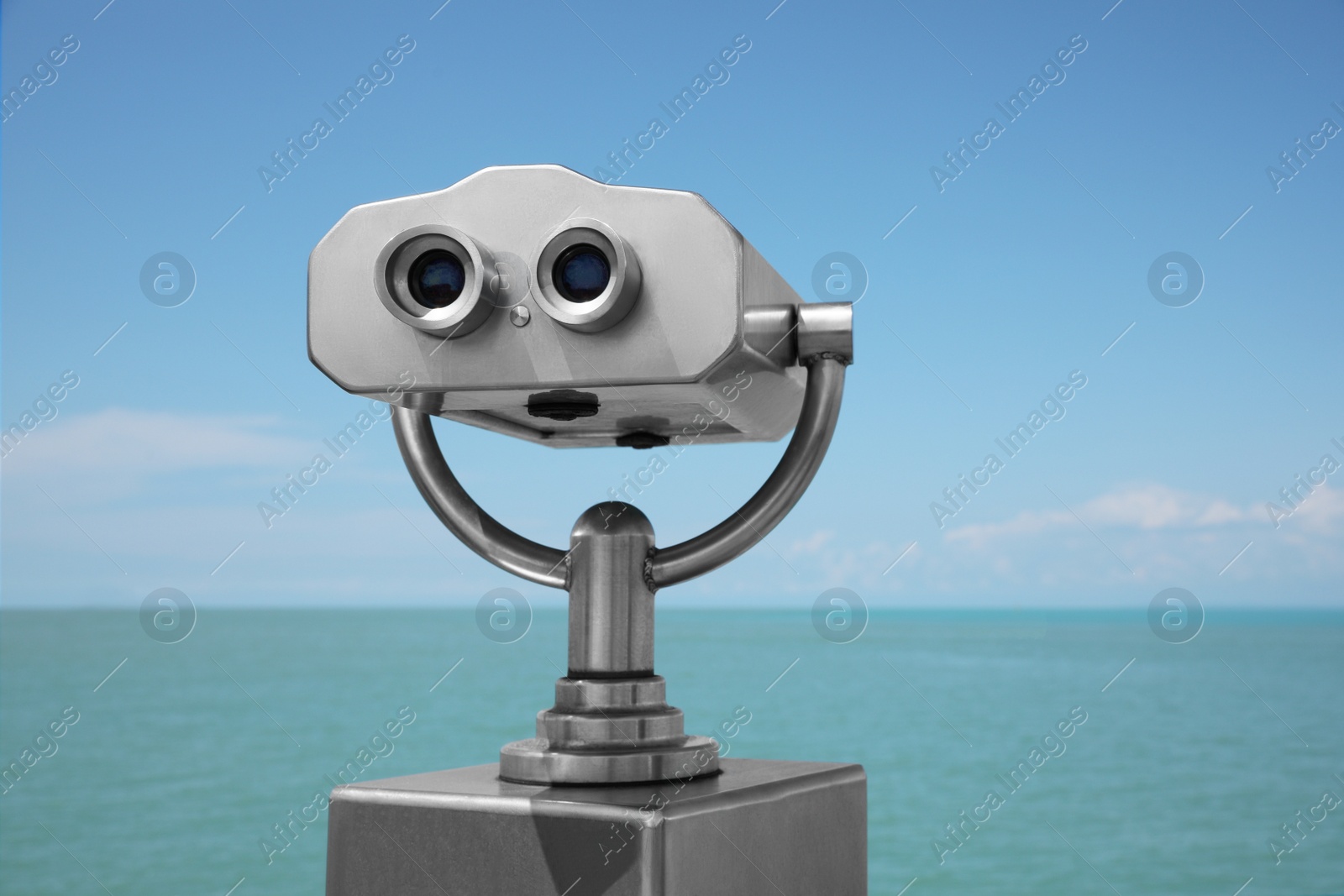 Photo of Metal tower viewer installed near sea. Mounted binoculars