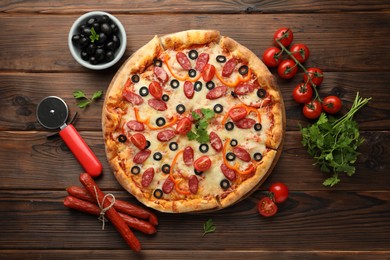 Photo of Tasty pizza, ingredients and cutter on wooden table, top view