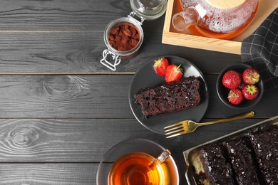 Photo of Tasty chocolate sponge cake served on black wooden table, flat lay. Space for text