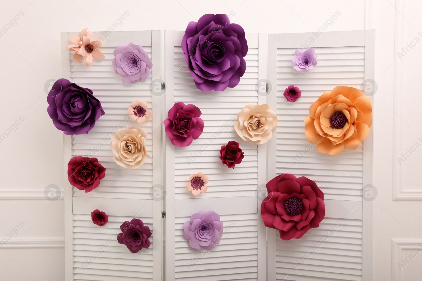 Photo of Beautiful paper flowers on folding screen indoors. Elegant photo zone