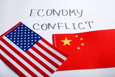 Photo of USA and China flags near words ECONOMY CONFLICT on white background