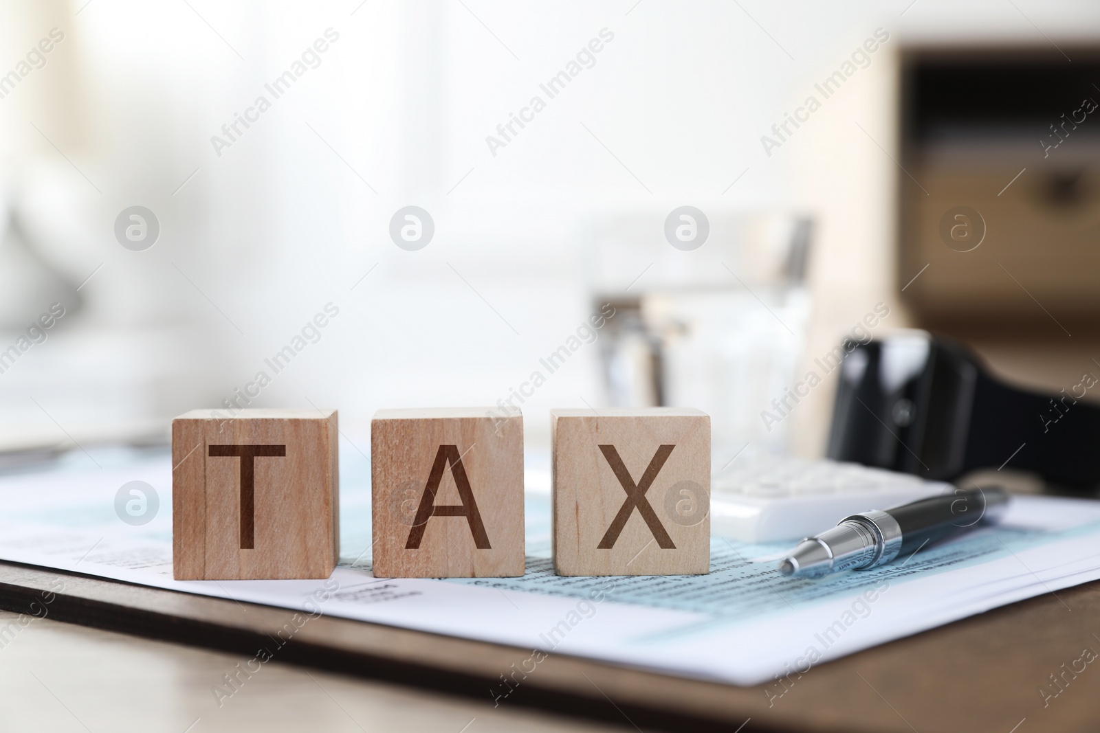 Photo of Wooden cubes with word Tax and document on table, closeup