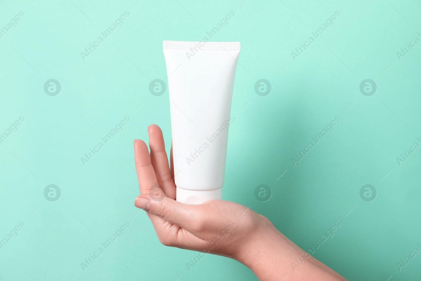 Photo of Woman with tube of hand cream on turquoise background, closeup