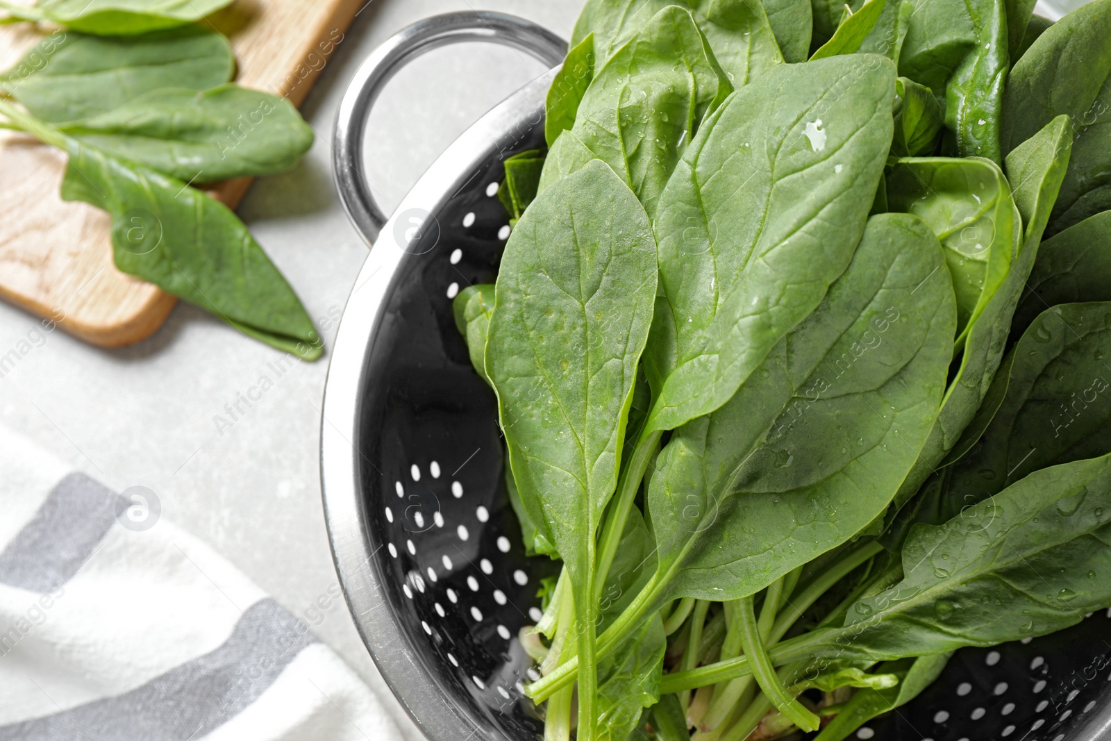 Photo of Colander with fresh green healthy spinach on grey table, top view