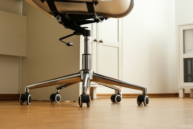 Photo of Modern office chair near table indoors, closeup. Stylish workplace interior