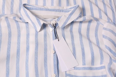 Blank white tags on striped shirt, top view. Space for text