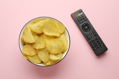 Photo of Remote control and bowl of potato chips on pink background, flat lay