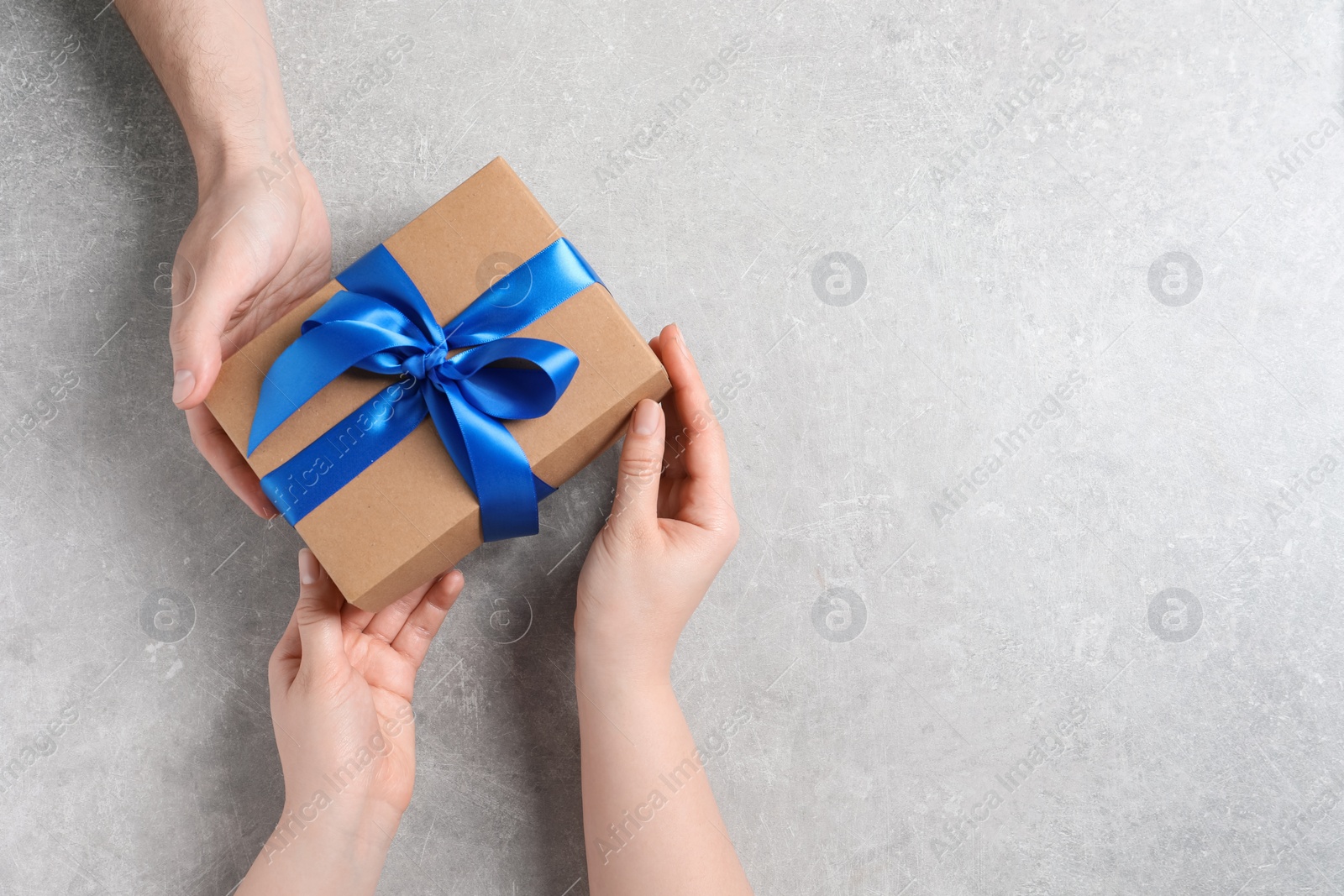 Photo of Man giving gift box to woman on light gray background, top view. Space for text