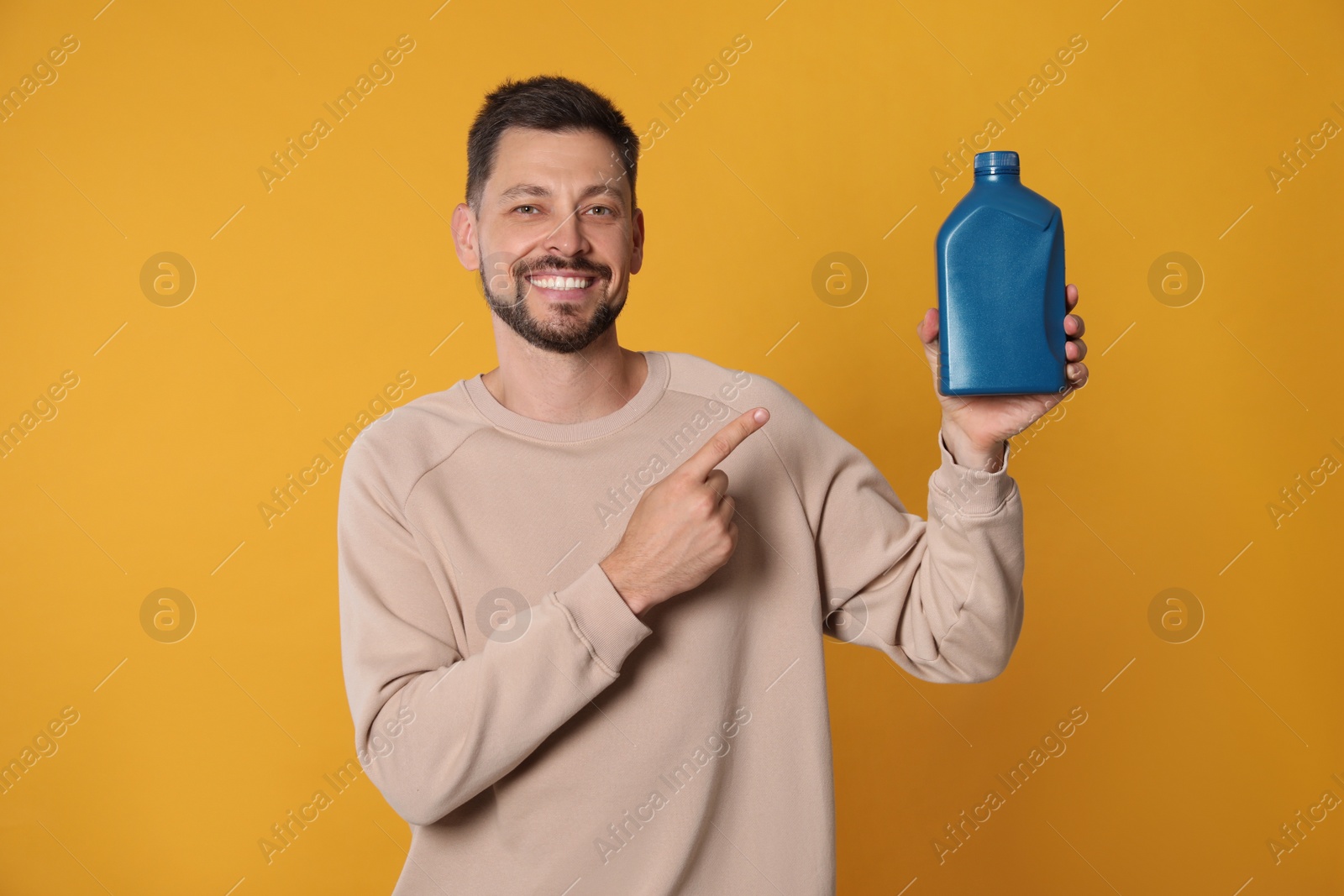 Photo of Man pointing at blue container of motor oil on orange background