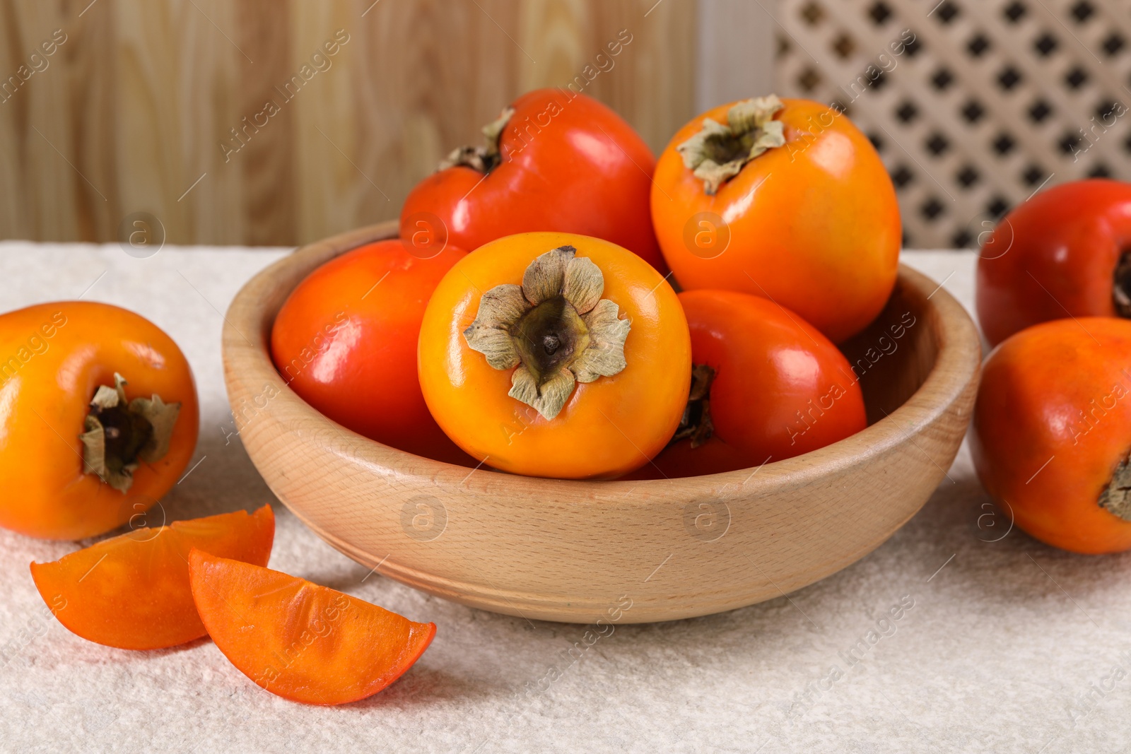 Photo of Delicious ripe persimmons on light textured table indoors, closeup