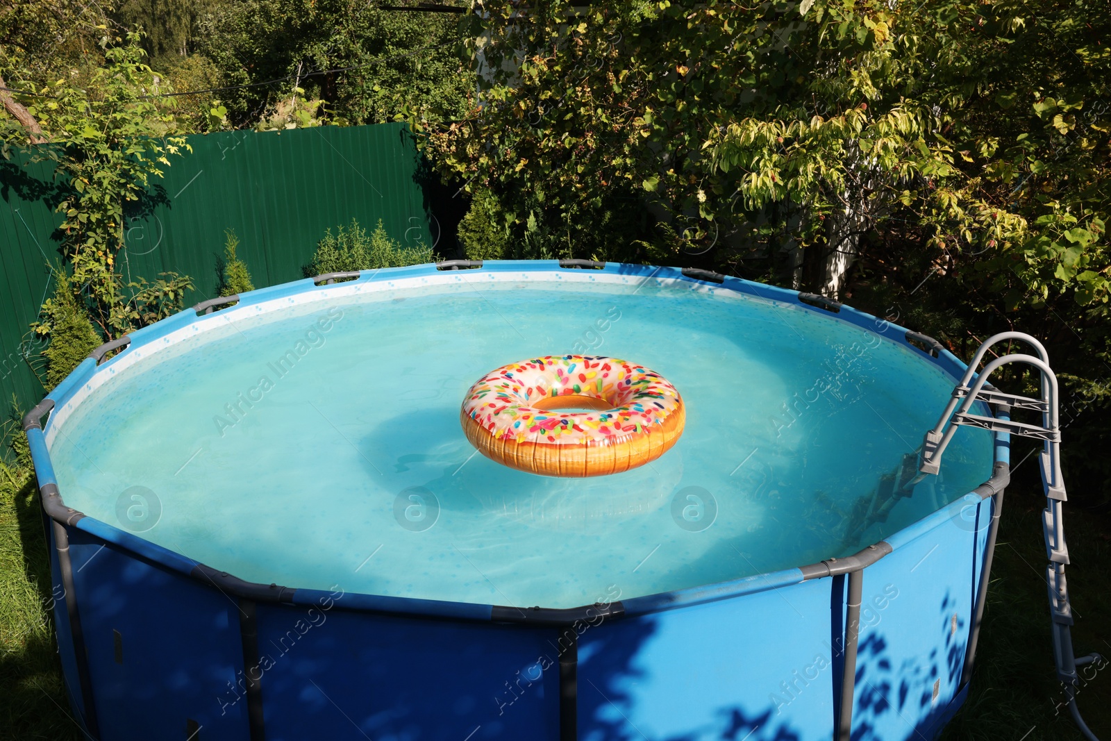 Photo of Inflatable ring floating on water in above ground swimming pool outdoors