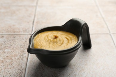 Tasty mustard sauce in saucepan on light tiled table, closeup