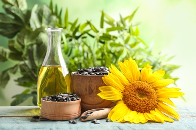 Photo of Composition with sunflower seeds, oil and flower on table