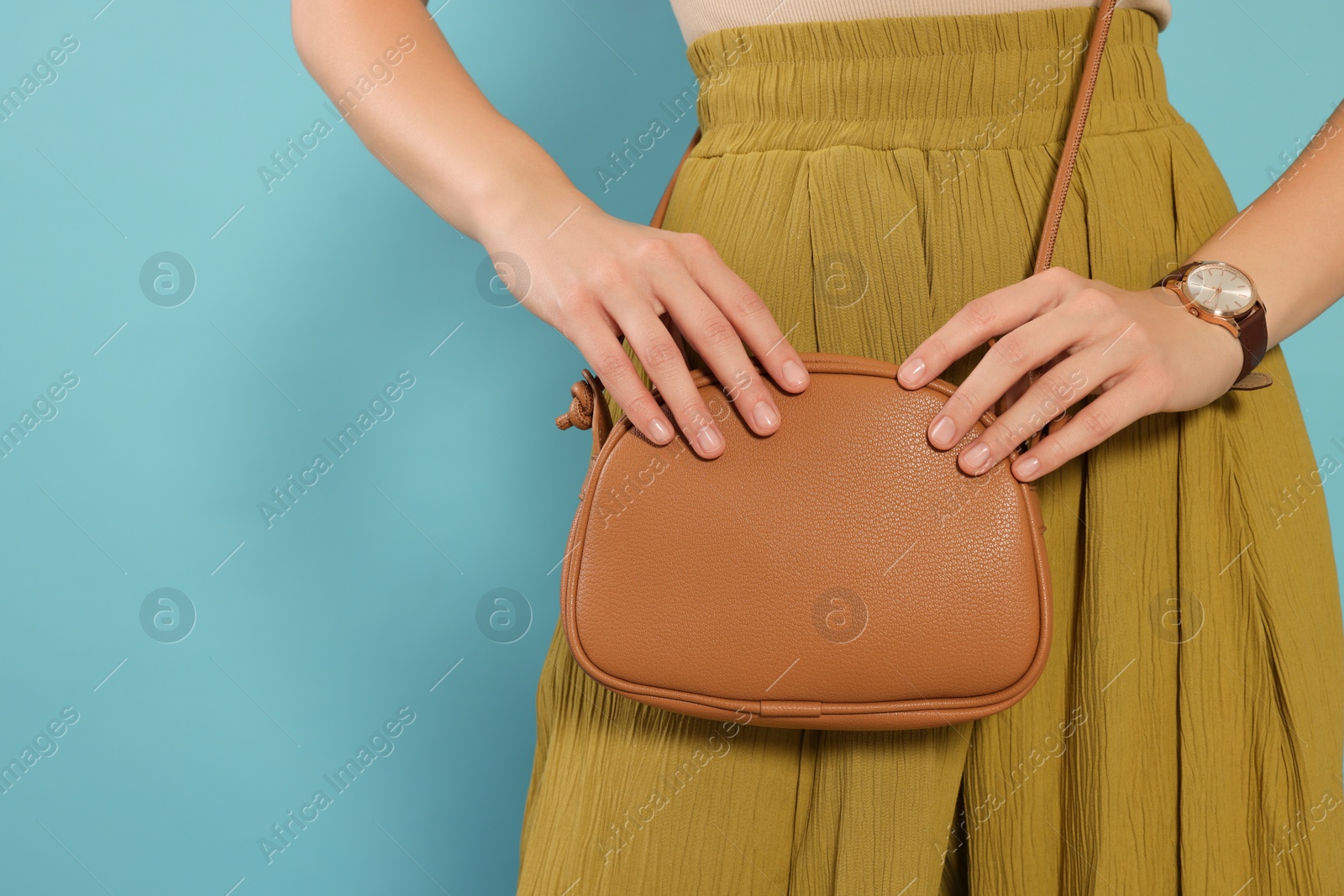 Photo of Woman with stylish bag on light blue background, closeup. Space for text