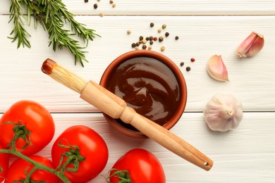 Flat lay composition with tasty barbeque sauce in bowl on white wooden table